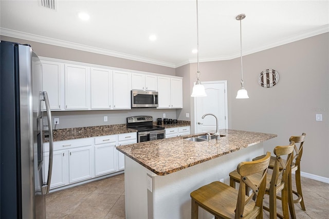 kitchen featuring a kitchen island with sink, sink, hanging light fixtures, white cabinetry, and stainless steel appliances