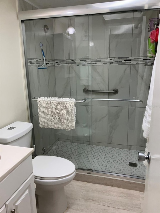 bathroom featuring vanity, a shower with shower door, and toilet