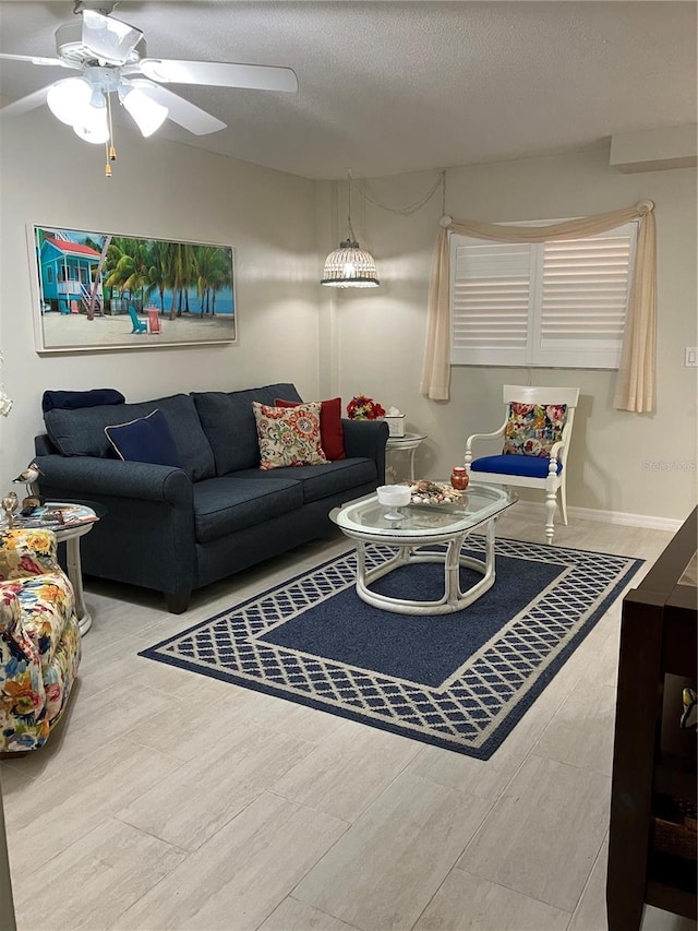 living room featuring ceiling fan and a textured ceiling