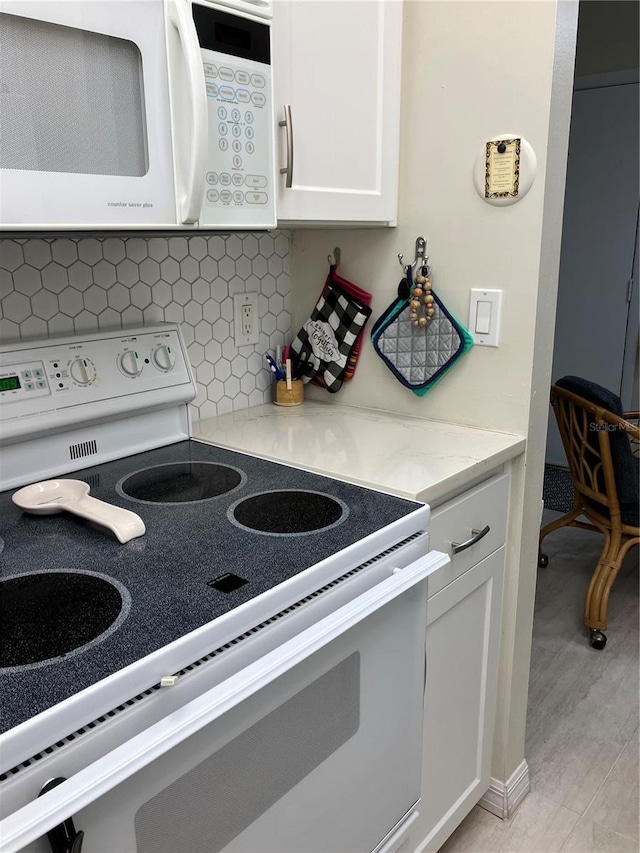 kitchen featuring backsplash, light stone countertops, white cabinets, and white appliances