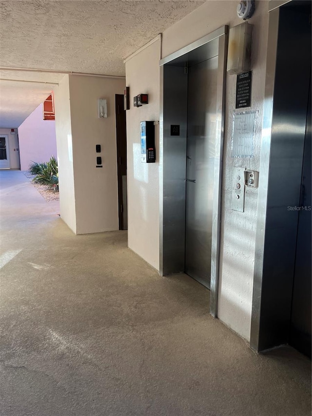 hallway featuring carpet, a textured ceiling, and elevator