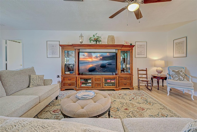 living room with a textured ceiling, light hardwood / wood-style floors, and ceiling fan