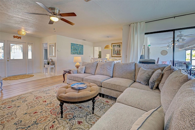 living room with a textured ceiling, light hardwood / wood-style floors, and ceiling fan