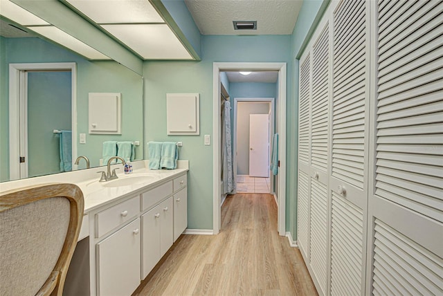 bathroom featuring hardwood / wood-style flooring, vanity, and a textured ceiling