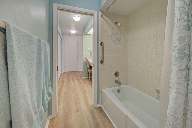 bathroom with shower / bath combo with shower curtain, wood-type flooring, and a textured ceiling