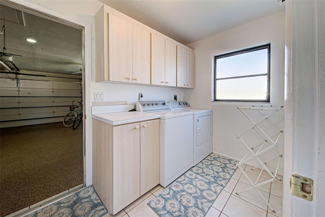 washroom featuring cabinets, washing machine and dryer, and light tile patterned flooring