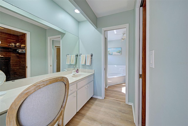 bathroom featuring hardwood / wood-style floors, vanity, ceiling fan, and a tub