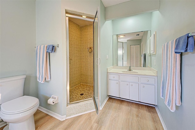 bathroom with hardwood / wood-style floors, vanity, toilet, and a shower with shower door