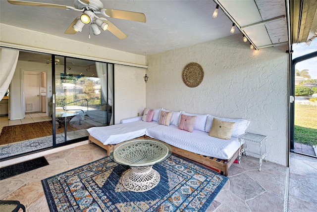 sunroom / solarium featuring ceiling fan and rail lighting