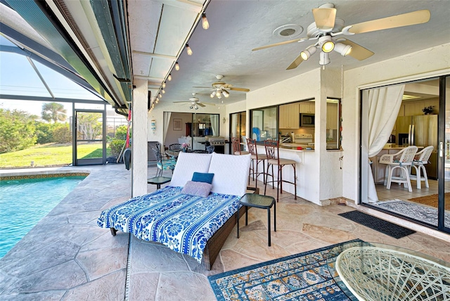 view of patio featuring glass enclosure, ceiling fan, and exterior bar