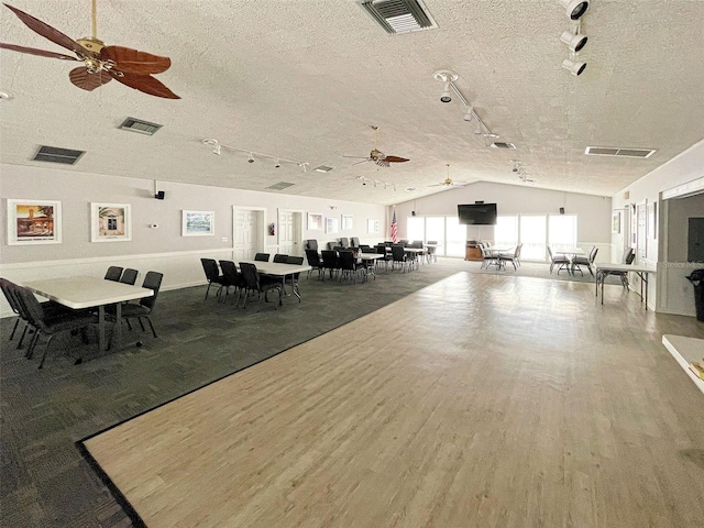 dining room featuring wood-type flooring, track lighting, ceiling fan, and lofted ceiling