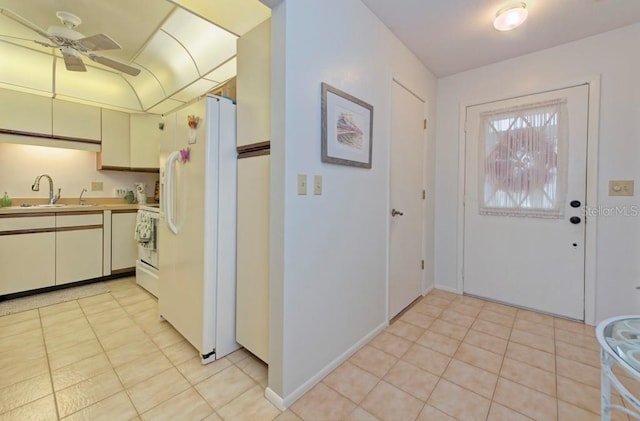 kitchen featuring ceiling fan, sink, cream cabinets, range, and white fridge with ice dispenser