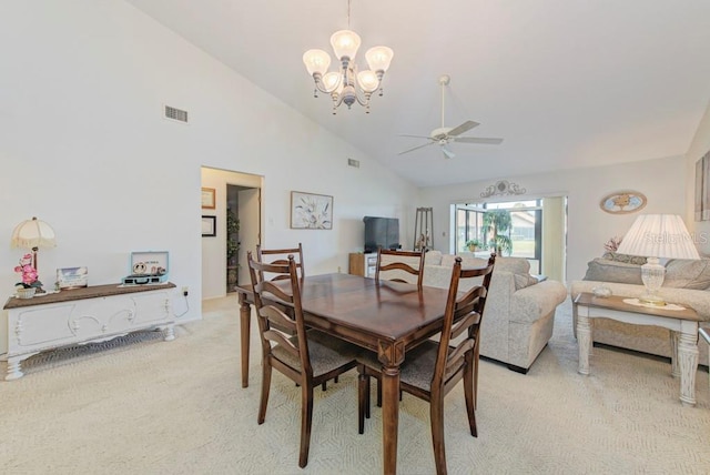 carpeted dining room with ceiling fan with notable chandelier and high vaulted ceiling