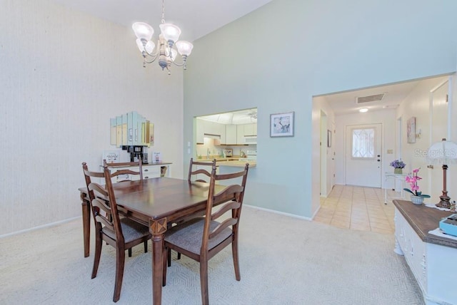 carpeted dining space featuring a towering ceiling and a notable chandelier