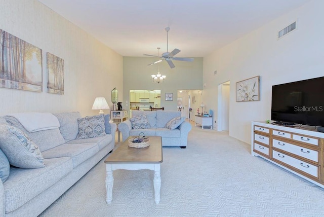 carpeted living room featuring ceiling fan with notable chandelier and a towering ceiling