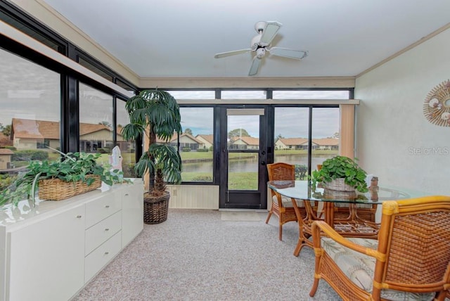 sunroom featuring ceiling fan and a water view