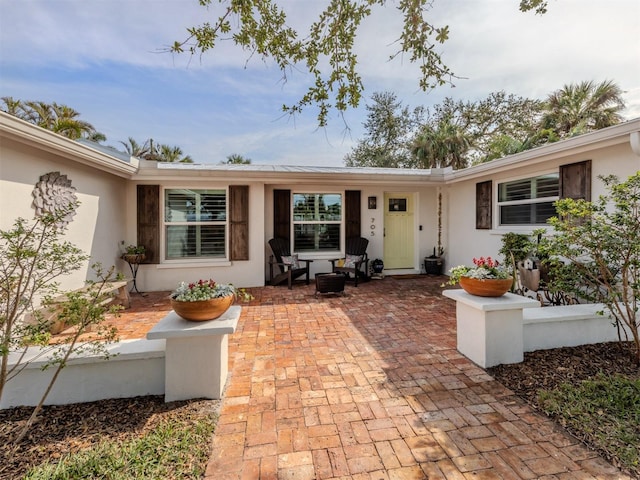 entrance to property with stucco siding and a patio