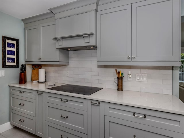 kitchen with black electric stovetop, gray cabinetry, and tasteful backsplash