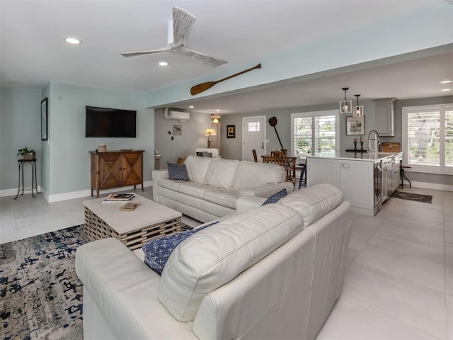 living area featuring a wall unit AC, recessed lighting, healthy amount of natural light, a ceiling fan, and baseboards
