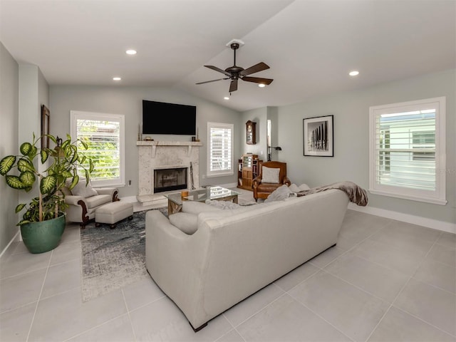 living area featuring baseboards, ceiling fan, a fireplace, vaulted ceiling, and light tile patterned floors