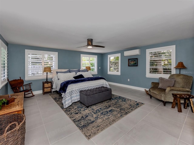 tiled bedroom with a wall unit AC, a ceiling fan, and baseboards