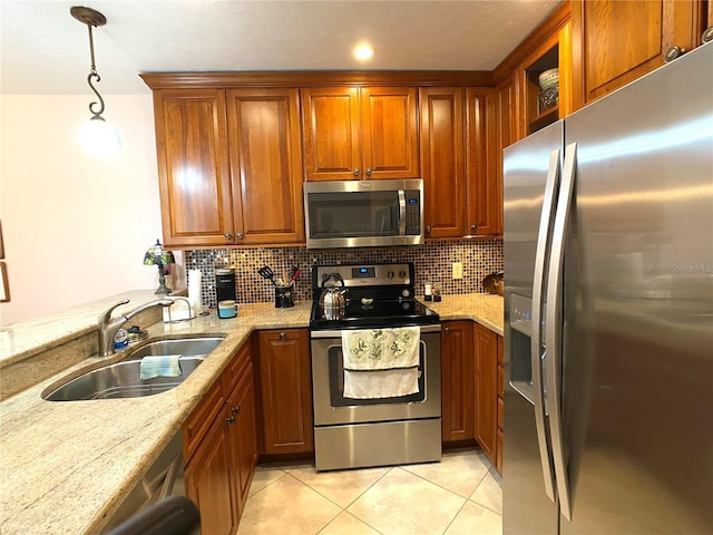 kitchen featuring light stone counters, sink, stainless steel appliances, and hanging light fixtures