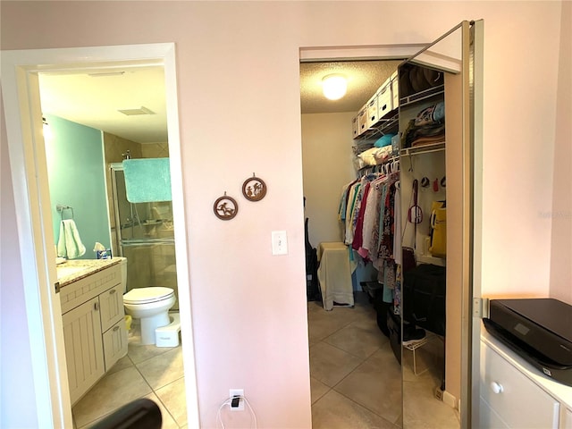 bathroom with toilet, vanity, tile patterned floors, and walk in shower