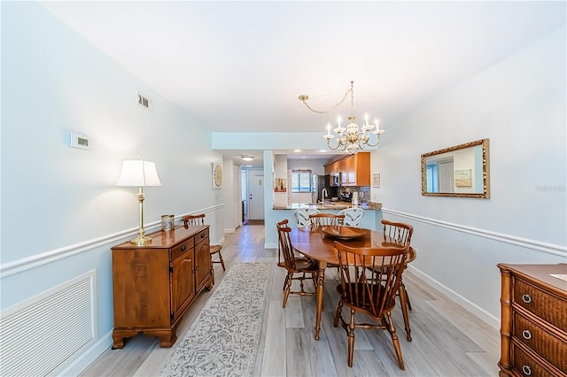 dining room featuring sink, light hardwood / wood-style flooring, and an inviting chandelier