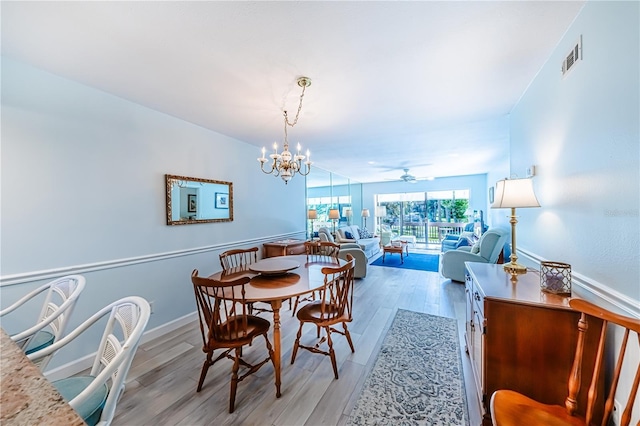 dining room with ceiling fan with notable chandelier and light wood-type flooring