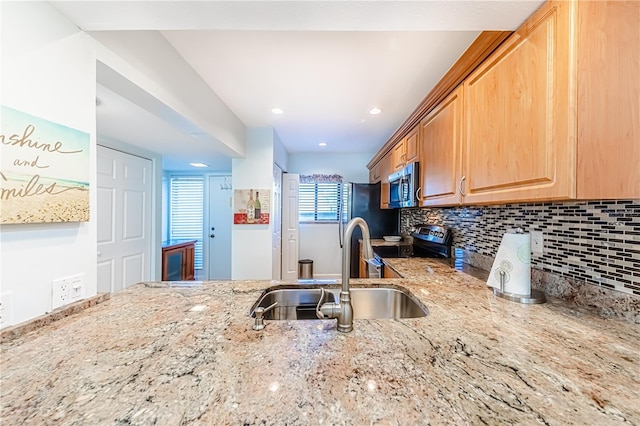 kitchen featuring decorative backsplash, sink, light stone countertops, and appliances with stainless steel finishes