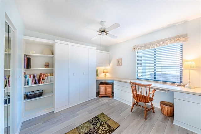 office area with built in desk, light hardwood / wood-style floors, and ceiling fan