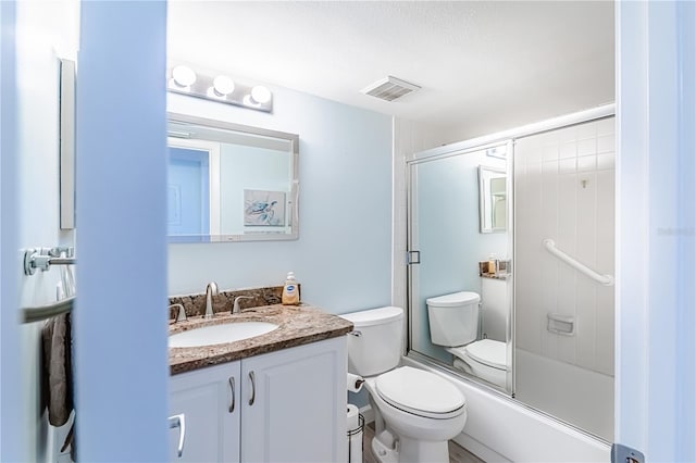 full bathroom featuring vanity, bath / shower combo with glass door, and toilet