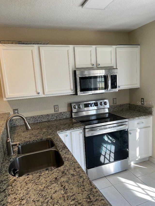 kitchen with dark stone countertops, stainless steel appliances, sink, and white cabinets