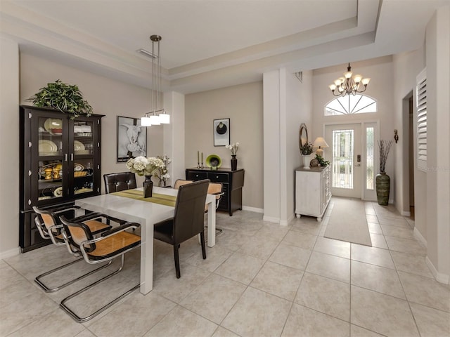 tiled dining room with a raised ceiling and an inviting chandelier