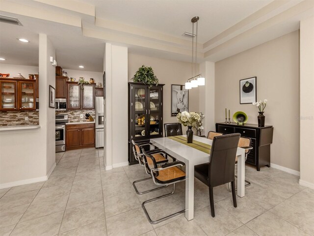 dining space with a raised ceiling and light tile patterned floors