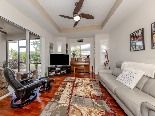 living room with ceiling fan, hardwood / wood-style floors, and a tray ceiling