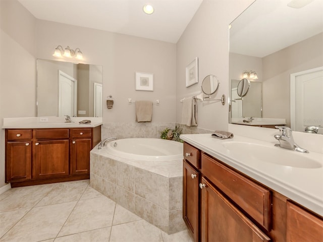 bathroom with tile patterned floors, tiled tub, and vanity