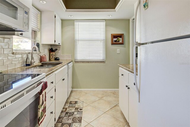 kitchen featuring sink, white appliances, light tile patterned floors, white cabinetry, and backsplash