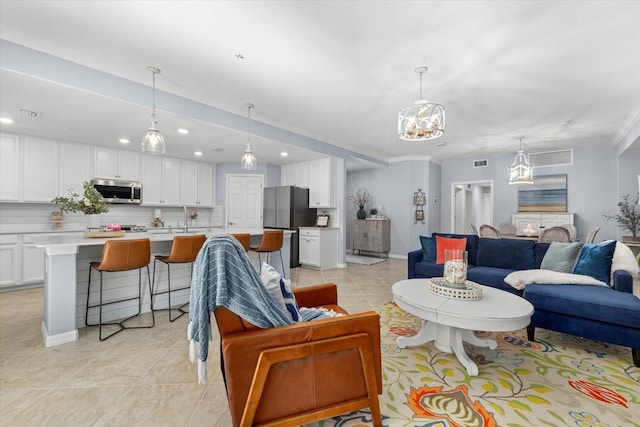 living room featuring light tile patterned floors, crown molding, and a notable chandelier