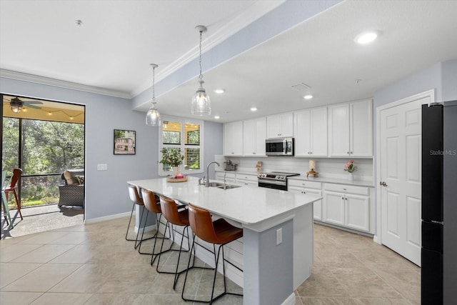 kitchen featuring appliances with stainless steel finishes, a kitchen island with sink, sink, white cabinetry, and hanging light fixtures