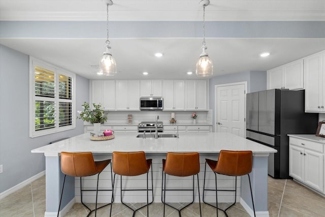 kitchen featuring backsplash, white cabinets, refrigerator, hanging light fixtures, and an island with sink