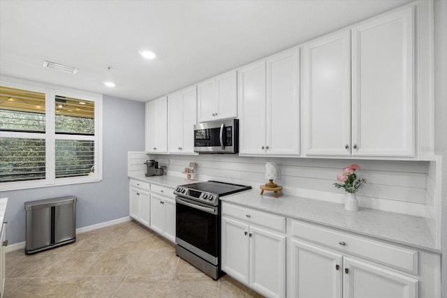 kitchen with backsplash, white cabinets, light stone countertops, light tile patterned floors, and stainless steel appliances