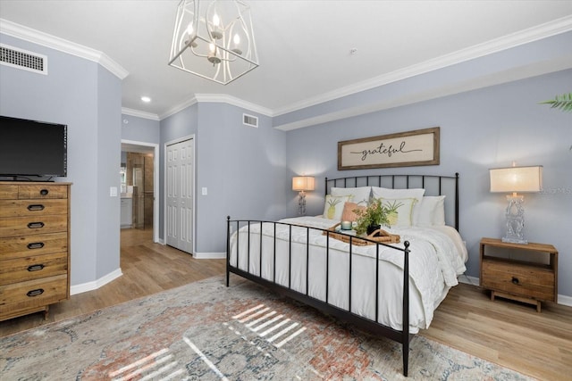 bedroom with crown molding, a closet, wood-type flooring, and a notable chandelier