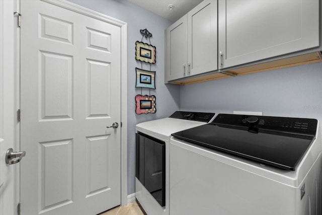 laundry room with cabinets, light tile patterned flooring, and washer and dryer