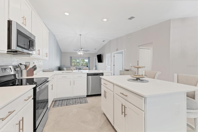 kitchen with ceiling fan, stainless steel appliances, a kitchen breakfast bar, kitchen peninsula, and white cabinets