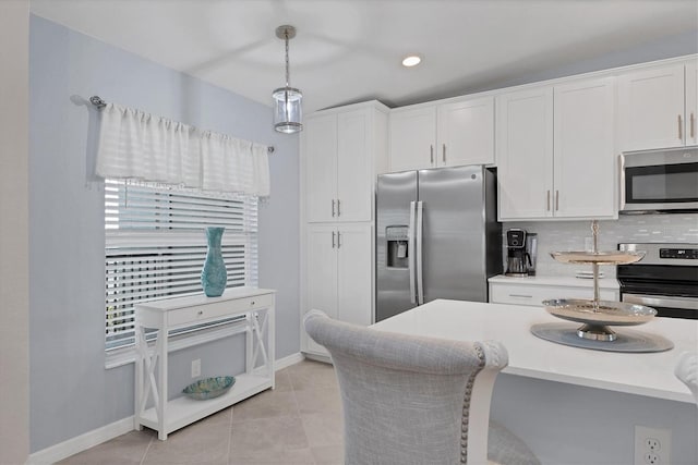 kitchen with decorative backsplash, appliances with stainless steel finishes, light tile patterned floors, white cabinets, and hanging light fixtures