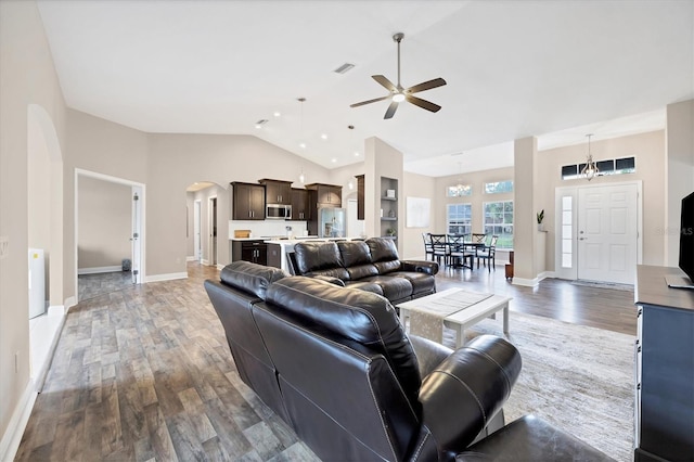 living room with ceiling fan with notable chandelier, dark wood-type flooring, and high vaulted ceiling