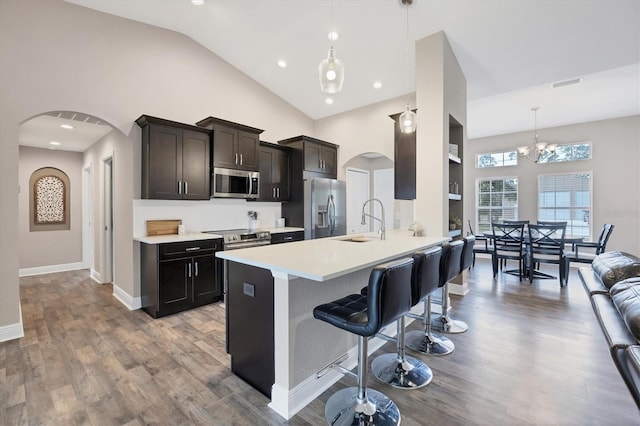 kitchen featuring a kitchen bar, appliances with stainless steel finishes, sink, decorative light fixtures, and a notable chandelier