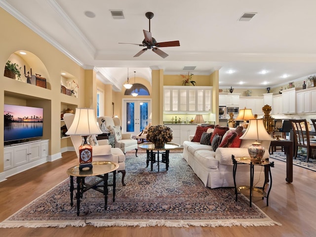 living room with built in shelves, ceiling fan, french doors, and wood-type flooring