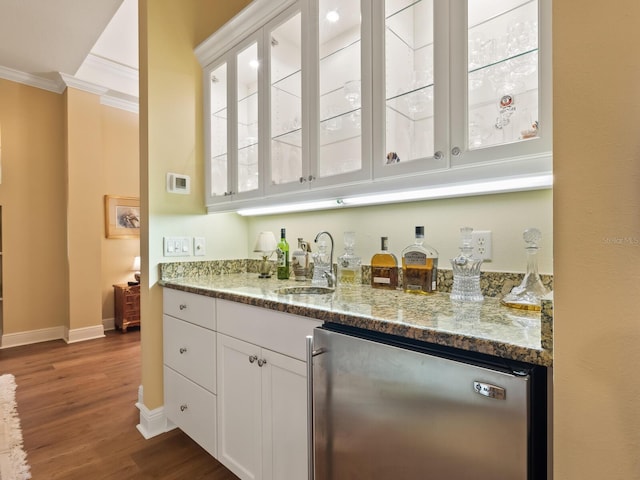 bar with dark hardwood / wood-style flooring, light stone counters, crown molding, sink, and white cabinets